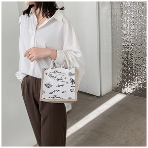 Close-up of canvas lunch tote with graffiti print and straw texture patchwork details