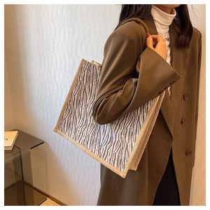 Detail of zebra print tote bag featuring woven edges and thick rope handles on model
