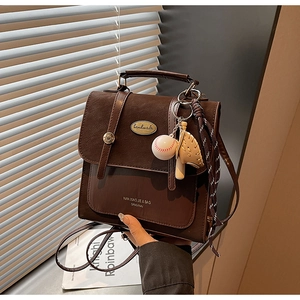 Detailweergave van de vintage bruine lederen rugzak met gespen en een baseball hanger
