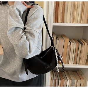Detail of black nylon hobo bag featuring silver zipper and cute bear charm pendant