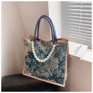 Detail of vintage floral jacquard tote bag with blue rope handle and pearl chain accent