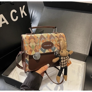Détails du tissage en losange sur sac en cuir marron avec charm de lapin en peluche