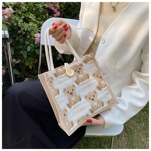 Detail of linen tote bag featuring a cute bear print and textured woven rope handles