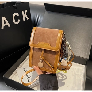 Close-up of brown leather crossbody bag with teddy bear pendant in luxury gift box