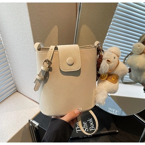 Détail du sac seau crème minimaliste avec charme de chien en peluche et cuir texturé