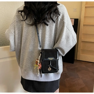 Detail of black PU leather mini crossbody bag with a bear charm and silk scarf accent