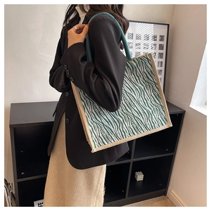 Detail view of the green zebra pattern canvas tote bag with woven rope handles on model