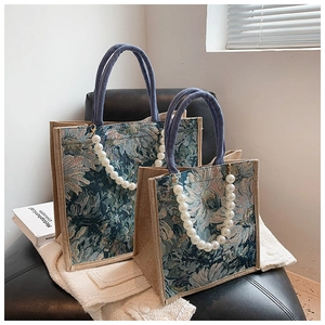 Detail of floral tapestry tote bags with blue rope handles and white pearl chain decoration