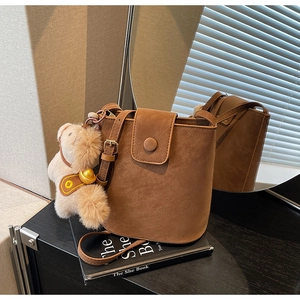 Détail d'un sac seau marron en daim avec breloque poney sur des livres d'art