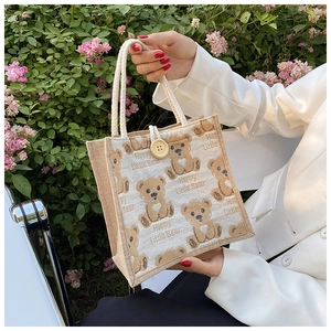 Close-up of linen tote bag featuring cartoon bears and a button closure with rope handles