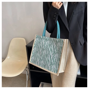 Detail of green zebra print tote bag with blue rope handles and woven linen texture