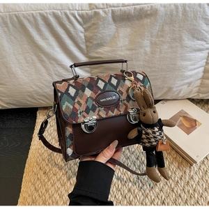 Détail du sac à bandoulière vintage à losanges avec breloque lapin et verrous argentés