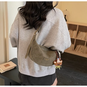 Olive green suede dumpling bag featuring an adjustable strap and a cute bear bag charm