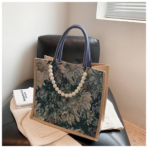 Close-up of floral jacquard tote bag with white pearl charm and blue woven handle