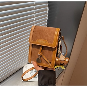 Detailed view of a brown retro crossbody phone bag with cute plush charm and metal pendant