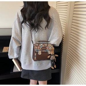 Détail d'un sac bandoulière marron matelassé avec un charm lapin et un fermoir en métal