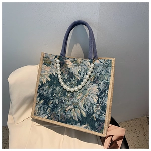 Detail of floral jacquard tote bag featuring decorative pearl chain and woven trim