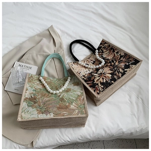 Detailed view of woven floral tote bags with decorative pearl and fabric handles
