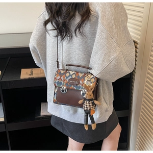 Détail d'un sac à bandoulière matelassé avec base marron et charmant pendentif lapin