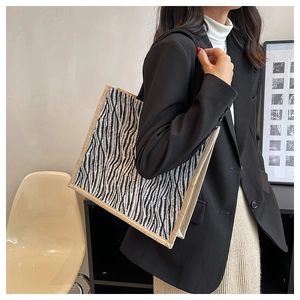 Detail of zebra print tote bag with beige woven edges and textured animal pattern finish