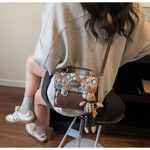 Détail du sac bandoulière à motif losanges avec cuir marron et pendentif lapin