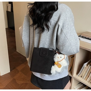 Détail du sac bandoulière carré en daim noir avec une jolie peluche d'alpaga blanc