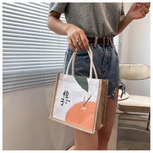 Detail of canvas tote bag with orange print, braided jute sides and thick cotton rope handle