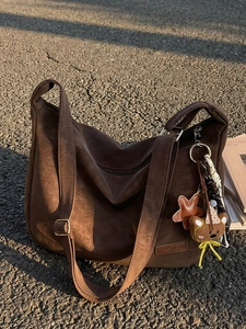 Sac hobo rétro marron grande capacité avec breloque ours sur un sol en asphalte