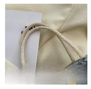 Detail of floral linen tote bag featuring woven rope handle and wooden button decoration