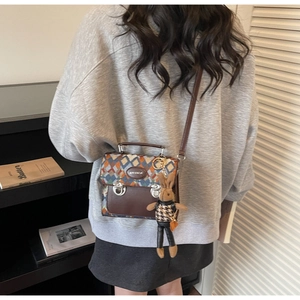 Détail du sac vintage tressé en losange avec base en cuir et breloque lapin en peluche