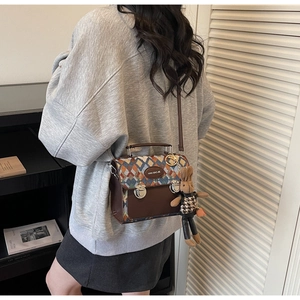Détail d'un sac bandoulière marron matelassé avec motif coloré et breloque lapin mignonne