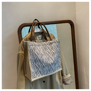 Detailed view of large zebra pattern tote bag with rustic woven rope handles on a coat