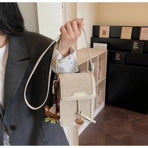 Detail of cream leather crossbody phone bag with gold trim and cute bear charm