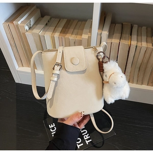 Vue détaillée du sac seau blanc crème avec fermeture à pression et breloque cheval