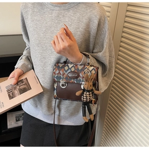 Détail du sac à bandoulière à motif de losanges avec un lapin en peluche et fermoir argent