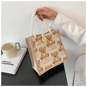 Detail of linen tote bag with cartoon bear print, cotton rope handle, and wooden button