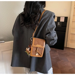 Brown crossbody phone bag with cute bear charm worn by a model in casual attire