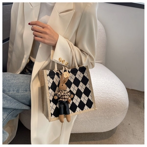 Detail of checkered linen tote bag with rope handles and cute rabbit charm decoration