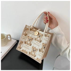 Detailed close-up of a linen tote bag featuring a cute bear print and wooden button closure