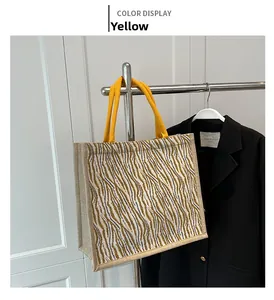 Detail of animal print tote bag featuring yellow rope handles on a black blazer
