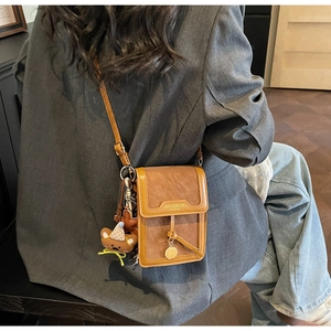 Detailed view of brown PU leather crossbody bag with logo and cute plush bear charm