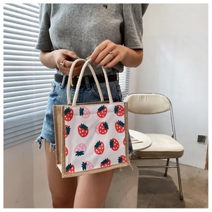 Detail of strawberry print canvas tote bag with rustic jute trim and sturdy handles