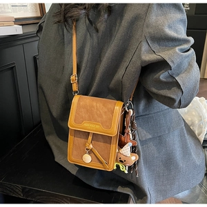 Detail of brown PU leather crossbody phone bag with star charm and plush bear pendant