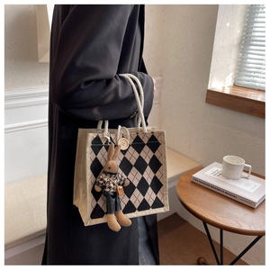 Detail of checkered linen handbag with large wooden button and rabbit plush charm