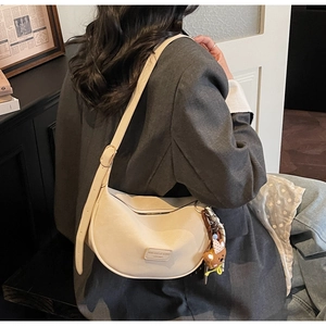 Detail view of cream dumpling bag on shoulder with cute bear pendant and wide strap