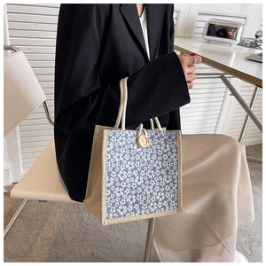Detail of floral linen tote bag with woven cotton rope handle and wooden button closure