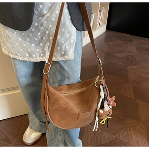 Brown matte leather crescent bag with adjustable strap and cute bear charm detailing