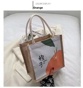 Detail van kleine jute lunchtas met oranje patroon en handgreep van zacht touw