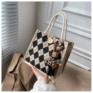 Close-up of woven argyle linen tote bag with cream rope handles and cute rabbit charm
