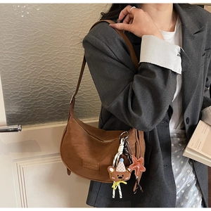 Detail of dark brown suede dumpling bag featuring plush bear and star pendants